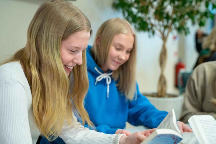 DSC05381 Två kvinnliga elever som läser varsin bok och ler