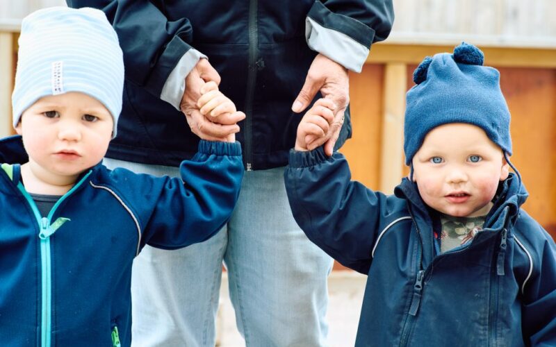 Två barn håller lärare i varsin hand