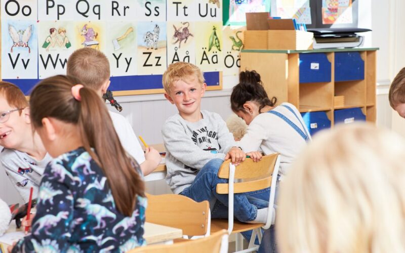 Elever i klassrum och en pojke kollar in i kameran